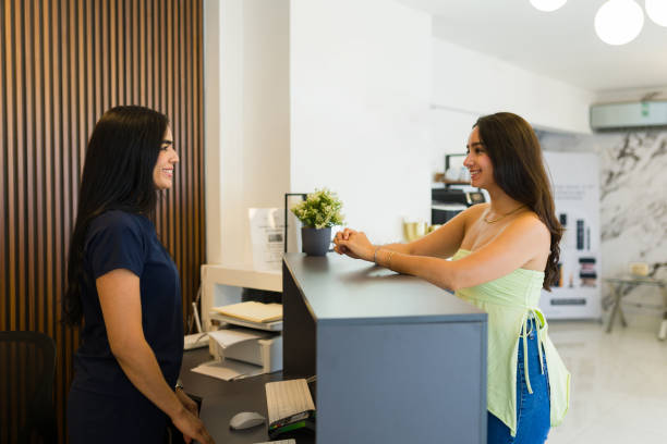 istock Cheerful female client being greeted by a smiling receptionist at a modern beauty clinic front desk 2156416913