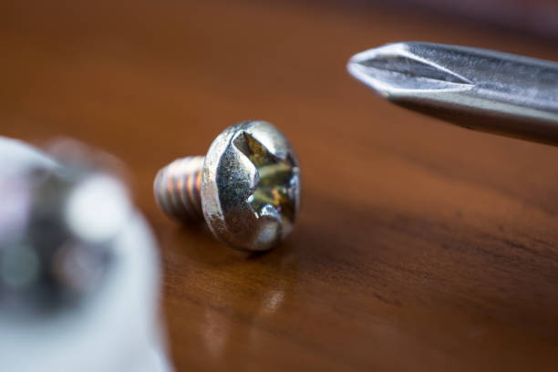 Metal screw with a metal screwdriver on a wooden table