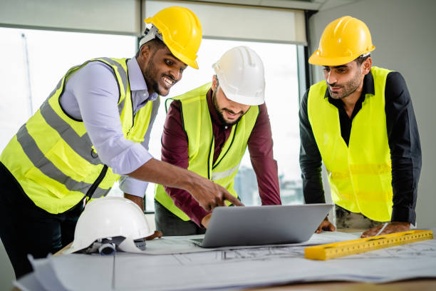 istock Team of Engineers diverse in safety suite discussing architectural projects with blueprints and laptop on the desk at the workplace, Developer real estate, teamwork, architecture, construction concept 2156420294