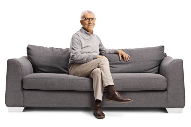 istock Elderly man sitting on a sofa and smiling 2156420479