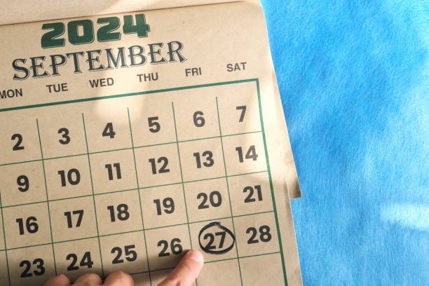 istock Hand pointing on September 27 2024 date on calendar flat lay in blue background. 2156437284