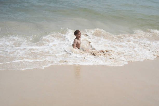 Boy plays in the sea at the beach.