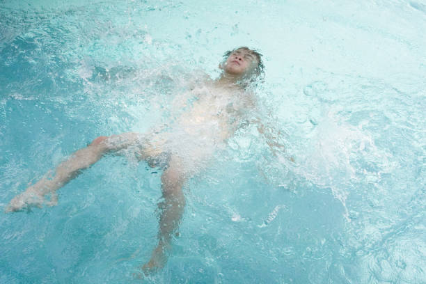 The picture shows a kid wearing a swim suit and cap getting ready before entering the pool for a swim.