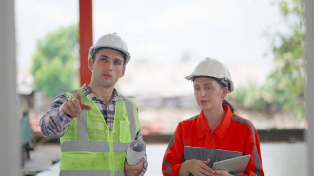 istock Professional construction manager or building contractor or engineer or foreman wearing safety uniform, discuss about house model and assembly of precast wall at construction site of bulidings or housing estate project. Worker is working in factory. 2156443089
