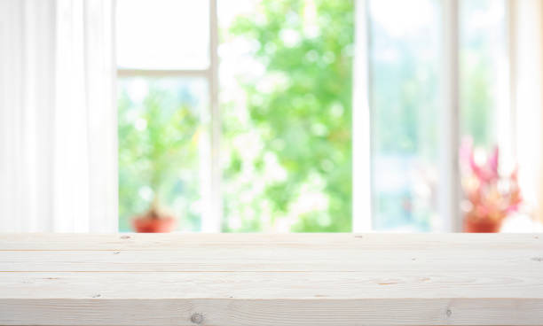 istock Empty wooden table top on blur curtained open window view on green summer garden background 2156450894