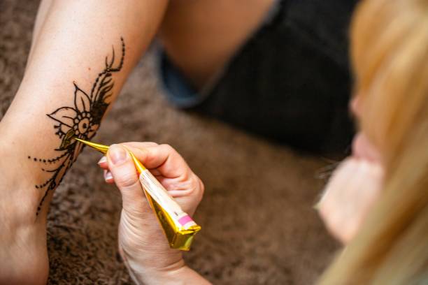istock Woman Applying Henna Tattoo on Ankle With Cone 2156454947