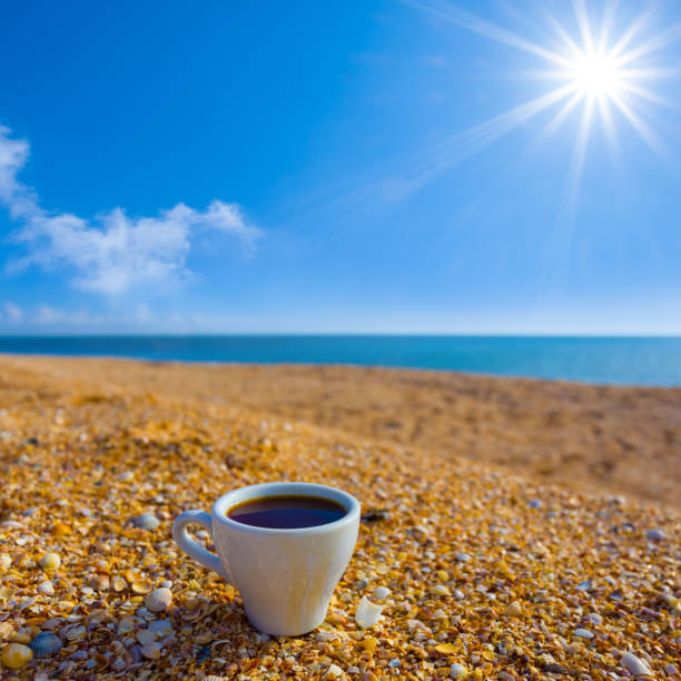 closeup  coffee cup stay on sandy sea beach at the summer sunny day