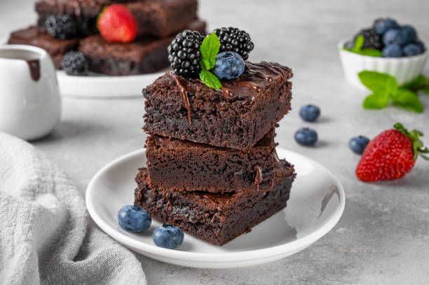 istock A stack of chocolate brownies with chocolate glaze, fresh berries and mint leaves on top on a white plate on a gray concrete background. Delicious dessert. 2156456866