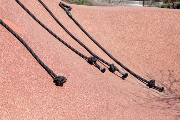 Climbing ropes with handles on a playground structure in bright sunlight