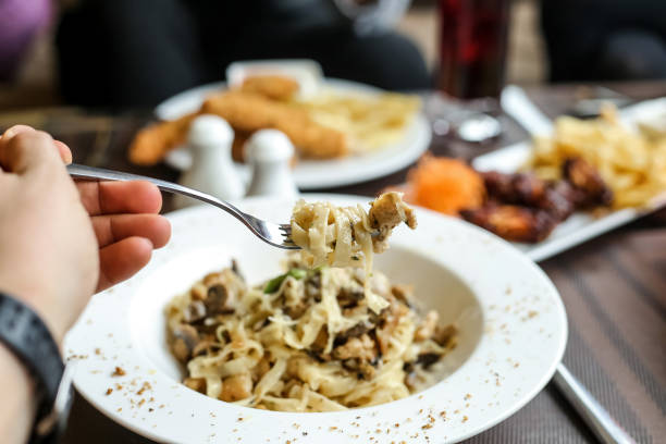 istock Person Holding Fork Over Bowl of Pasta 2156459002