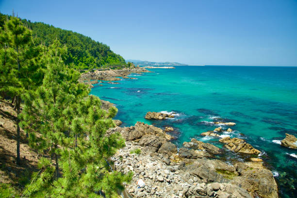 Samcheok City, South Korea - May 18, 2024: The stunning rocky coastline along Isabu Road, featuring vibrant turquoise waters and lush greenery, viewed from the observation deck at Beach Sculpture Park.