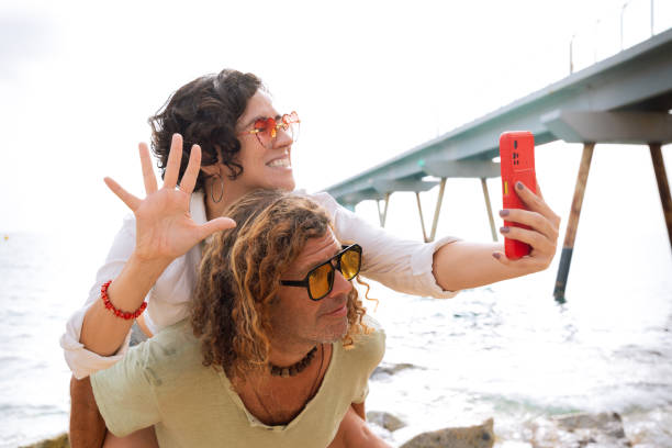 istock Smiling couple on beach vacation talking on video call with a friend. 2156465471