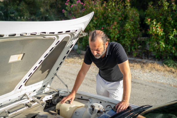 istock Young man's classic car broke down on the road, he looks at the engine compartment and thinks about the breakdown, he is anxious and stressed 2156466061