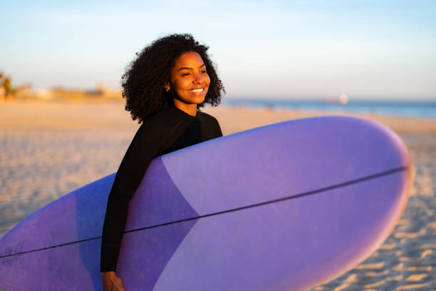 istock Joyful Black Female Surfer with Surfboard at Beach 2156467725