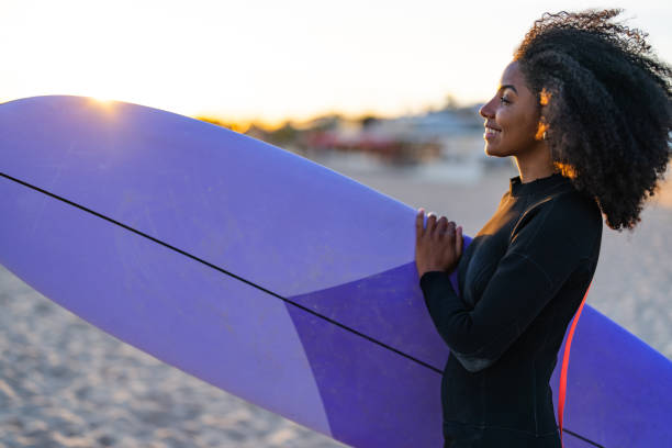 istock Joyful Black Woman with Surfboard on Coastal Sands 2156467744