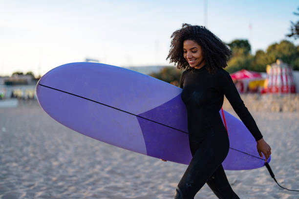 istock Joyful Black Female Surfer with Board on Beach 2156467760