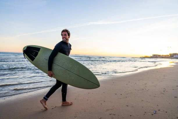 Smiling Surfer Walking on Beach at Dusk