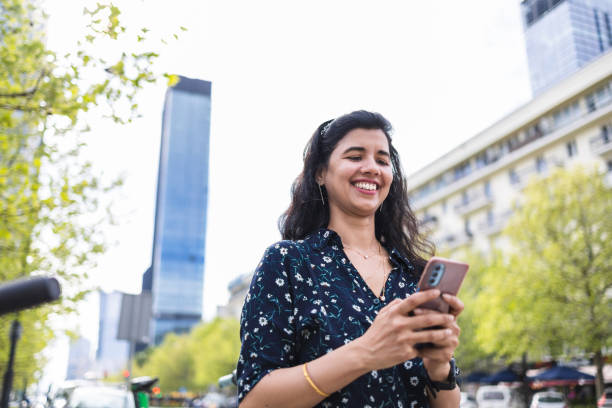 istock Smiling young woman using her smartphone in the city 2156470219