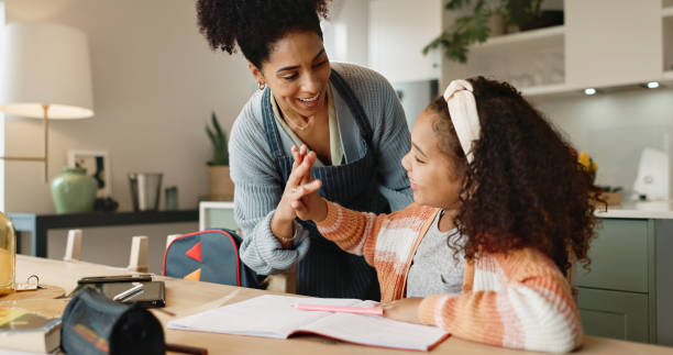 istock Child, high five and house for education, learning and growth for future or knowledge. Mother, student and kitchen for help, studying and support or home school for development or coloring assessment 2156473476