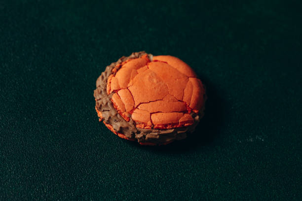 istock broken sweet, orange macaroon on a green background 2156474082