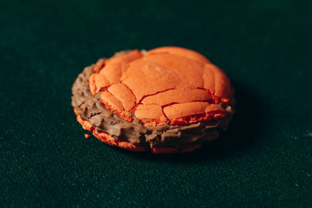 istock broken sweet, orange macaroon on a green background 2156474084