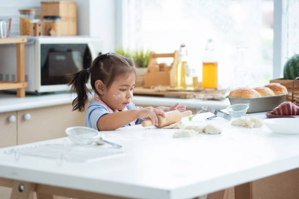 istock Pretty little girl having fun kneading dough with a rolling pin 2156475759