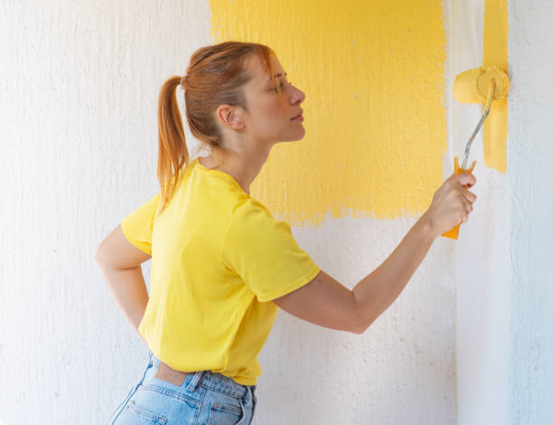 istock Young women painting a wall with paint roller 2156477984
