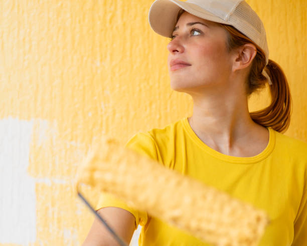 istock Young women painting a wall with paint roller 2156478178