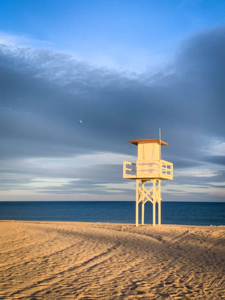 istock Lifeguard tower on sandy beach overlooking sea at sunset 2156478427