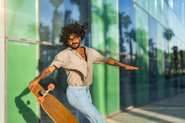 istock Hispanic Male Performing Longboard Trick by Glass Building 2156488696