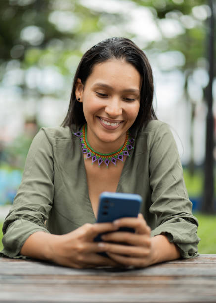 istock young latin woman smiling and using her cell phone 2156491554