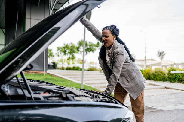 istock Stressed woman looking at engine of a broken car 2156493344