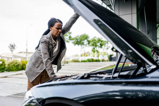istock Stressed woman looking at engine of a broken car 2156493565