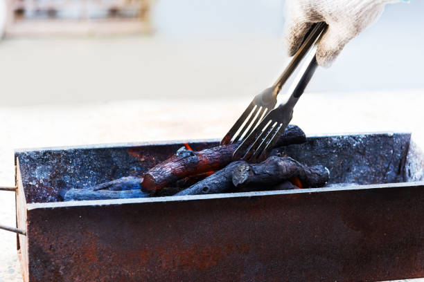 The gloved hand is holding a clip and holding charcoal