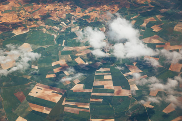 Patchwork landscape with white clouds covering a little village. Aerial view from fertile land Spain. Satellite or aircraft view. Raining over my head concept. High quality photo