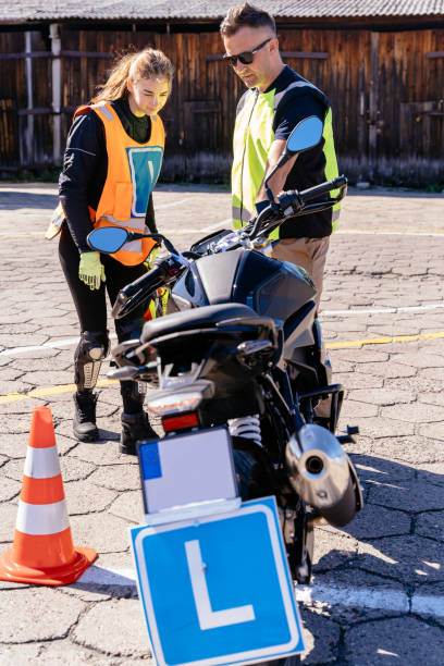 istock Motorcycle driving practice. Learner motorcyclist practicing to ride a moto. Learner biker on test road with red cones. Instructor writing on clipboard his points. 2156500900