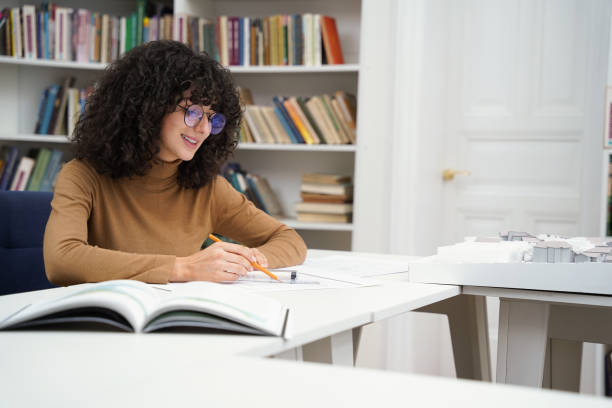 istock Woman architect working with blueprints in a well-stocked library 2156501606