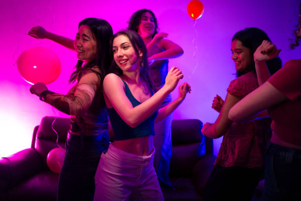 A medium-wide shot of five diverse university students partying in a living room. They are all dancing and smiling. They are all wearing casual clothing in a student house in Durham in the North East of England.\n\nVideos are available similar to this scenario.