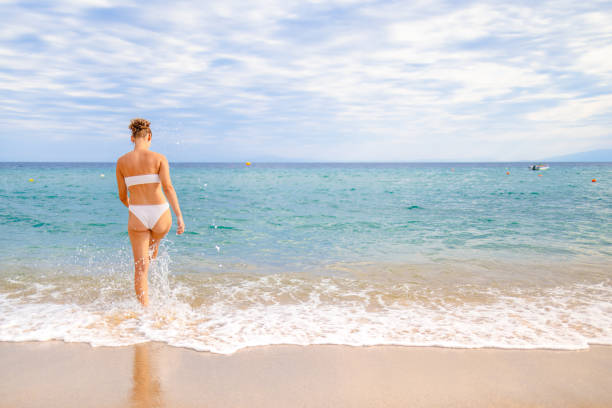 istock Unrecognizable young Caucasian woman playing with waves on the beach 2156505025