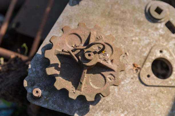 Gearwheel with cotter pin of the chain drive and carcass part of an old abandoned rusty agricultural machine, close-up in selective focus outdoors
