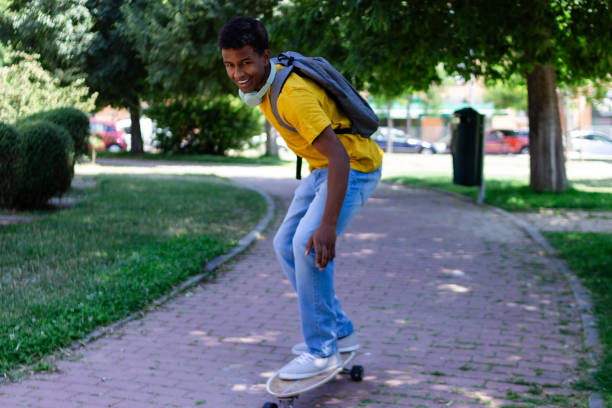 Young student is having fun after school, riding his skateboard in a park