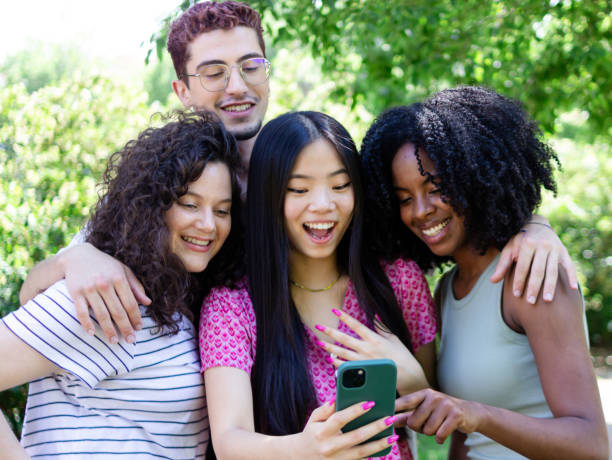istock Group of friends having fun using smartphone outdoors in a park 2156510116