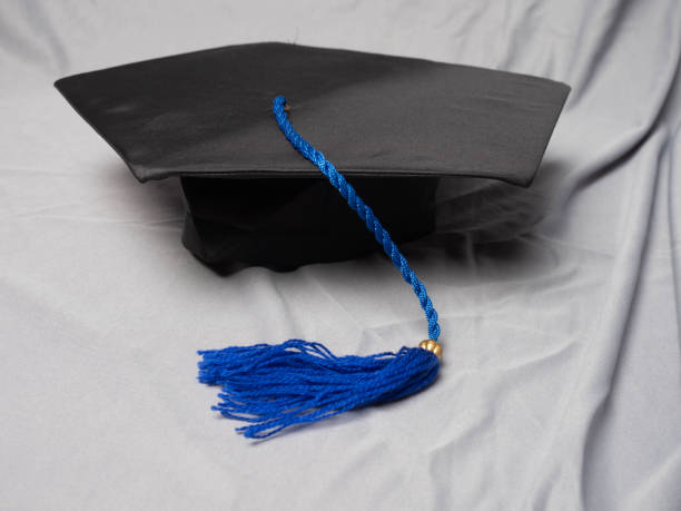 istock Black mortarboard with blue tassel on a grey cloth background 2156513150