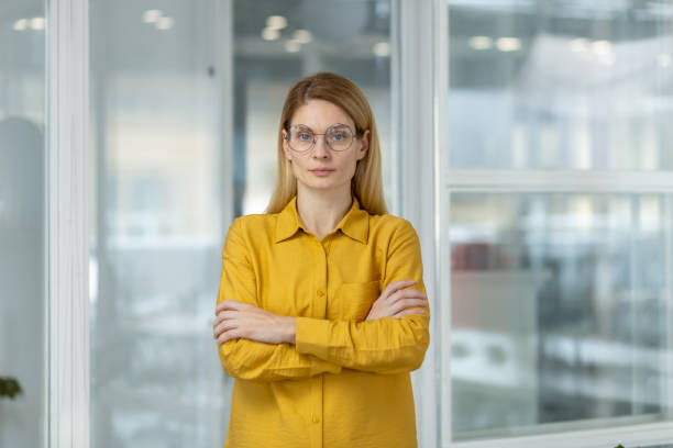 istock Confident businesswoman with glasses standing in modern office while looking at camera 2156513217