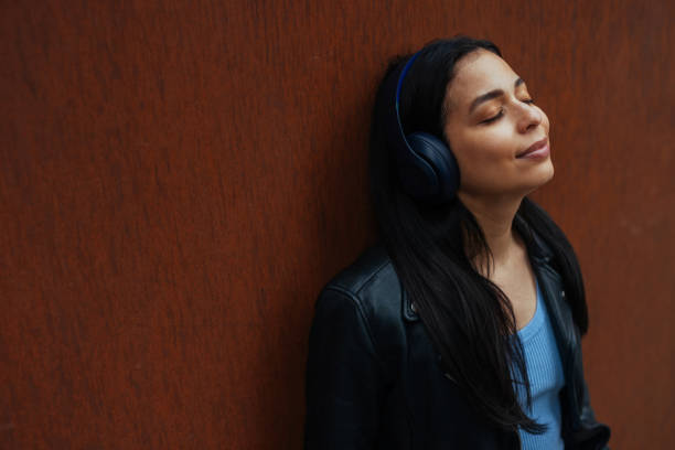 istock Pretty young woman in a leather jacket leaning against a wall 2156515624