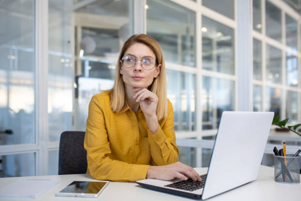 istock Thoughtful businesswoman working on a laptop in a modern office setting 2156518214