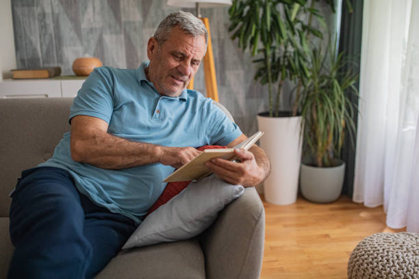 istock An elderly man is reading a book, enjoying his free time 2156518350