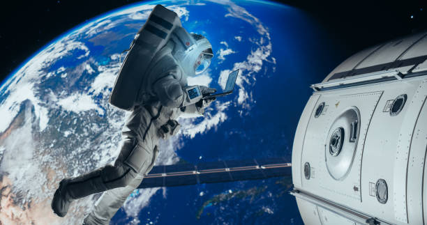 istock Male Astronaut Using a Laptop to Wirelessly Connect to a Satellite. Spaceman Working on a Device in Open Space Outside Earth Atmosphere. Professional Engineer Undertaking Service and Maintenance Job 2156519156