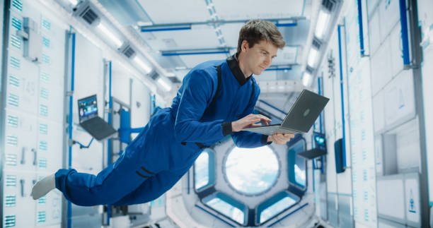 istock Male Astronaut Using a Laptop to Wirelessly Connect to a Satellite. Space Scientist Working on a Computer Device Inside an Intergalactic Station. Professional Engineer Undertaking Online Service Job 2156519189