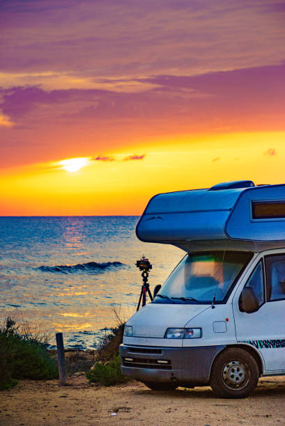 istock Camper and camera on tripod on beach at sunrise 2156519814